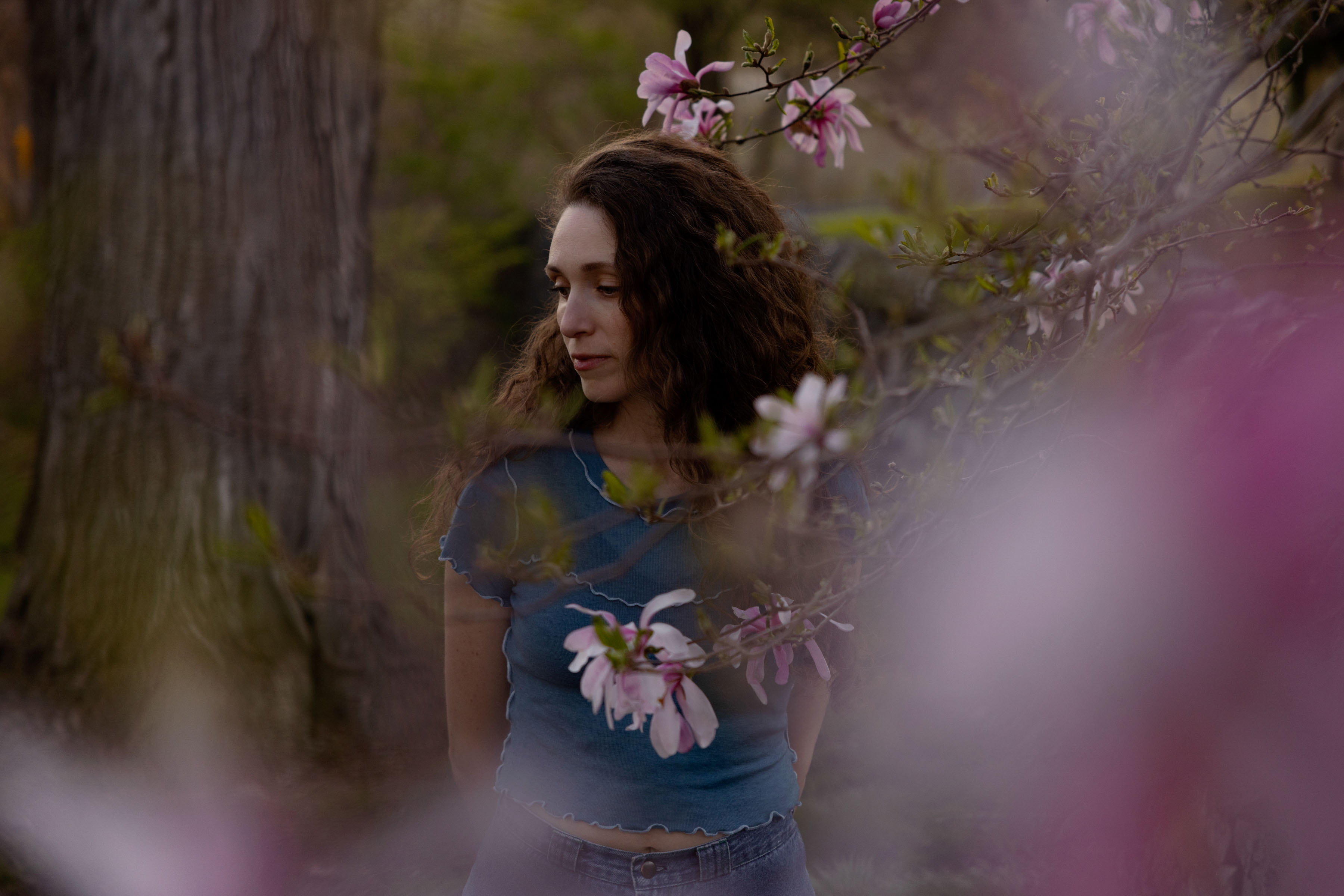 A young woman photographed between the branches of a magnolia tree